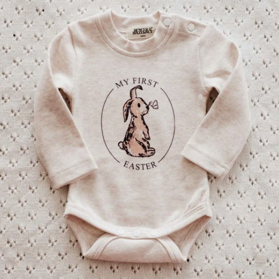 Baby onesie with 'My First Easter' bunny design on a textured surface