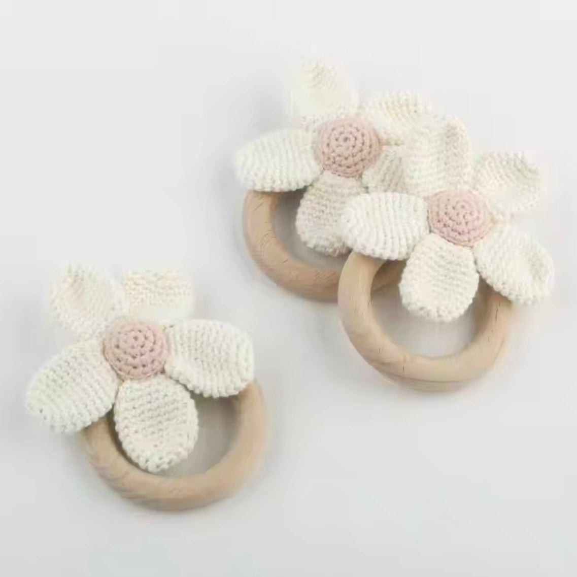 Two wooden teething rings with floral designs on a light gray background