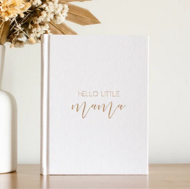 White card with 'Hello Little Mama' text next to a vase with flowers on a light surface.