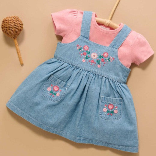 Children's denim dress with pink top on a beige background