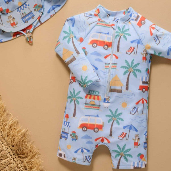 Children's swimsuit with beach theme and matching hat on a beige background